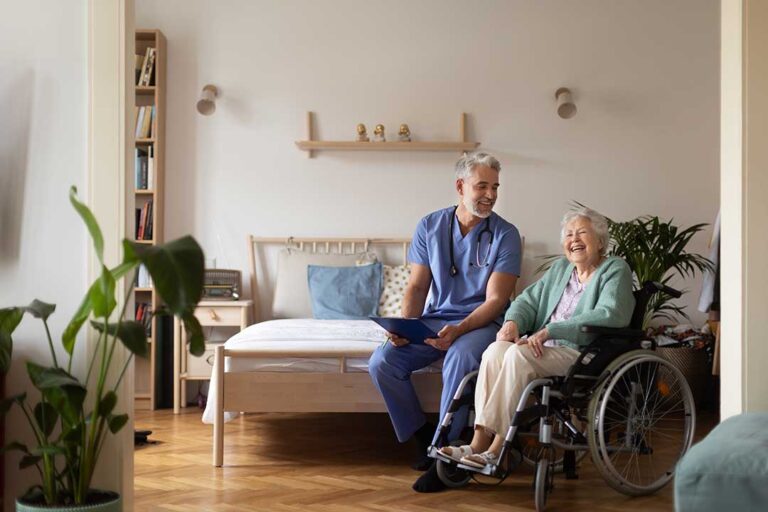 Older adults sharing a meal and conversation in a bright assisted living dining room.